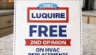 The image shows a kitchen counter sign offering a free second opinion on HVAC replacements. The sign features bold text and a simple design.